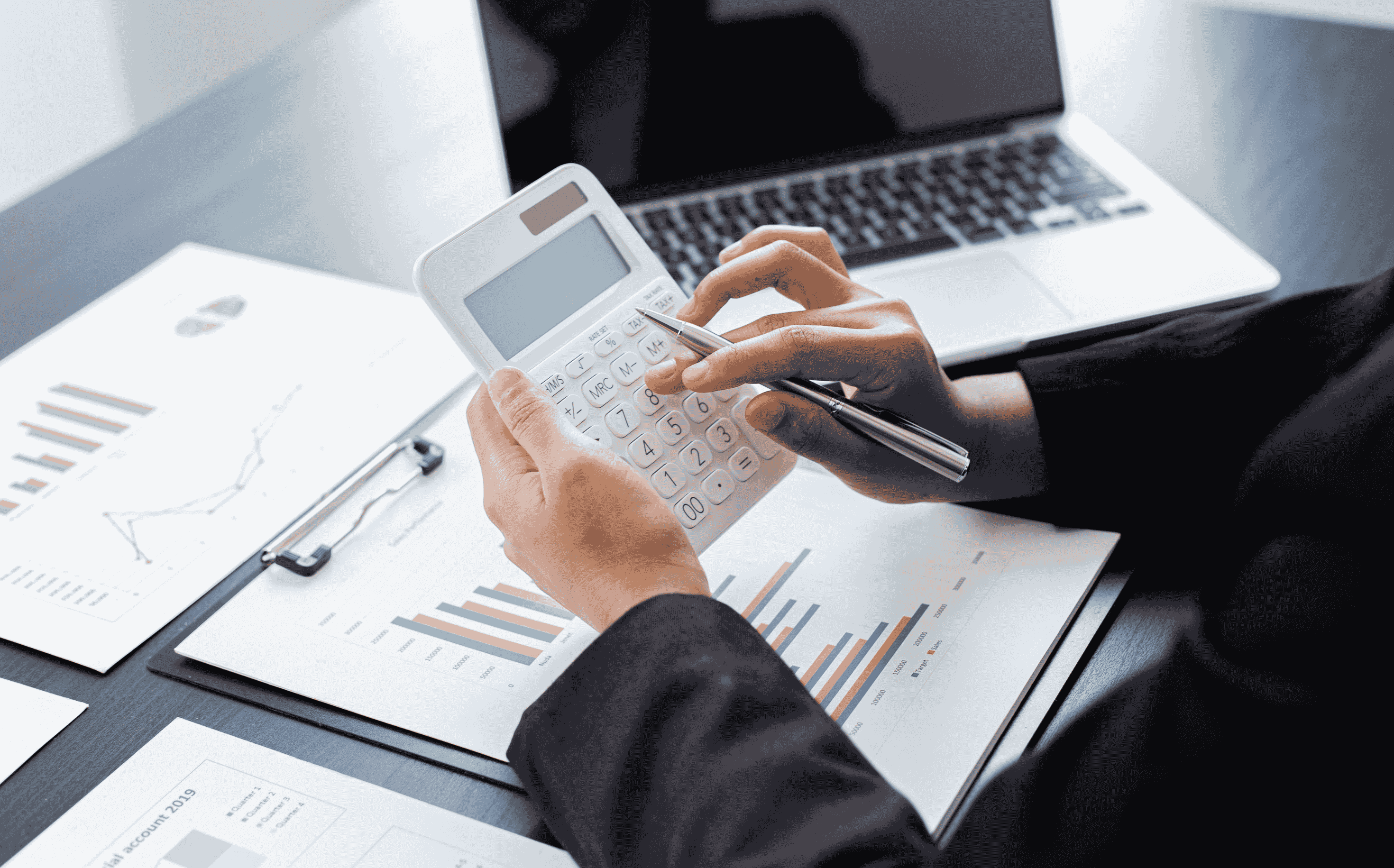 Calculator in use beside open laptop